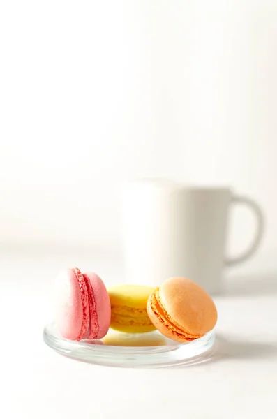 Delicious delicate multicolored macaroons on a platter with a cup of coffee in the background with place for text. close-up. selective focus. — Stock Photo, Image