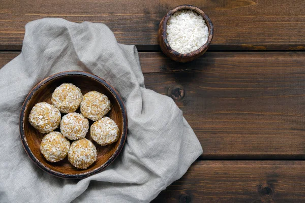 Sporcular için sağlıklı atıştırmalıklar. Kurutulmuş yulaf ezmesinin doğal malzemelerinden yapılmış ev yapımı sağlıklı enerji topları seramik tabaktaki şekersiz hindistan cevizli kurutulmuş meyveli fındıklar..