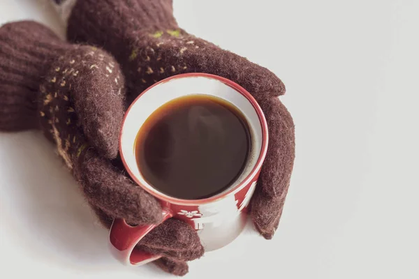 Hands in brown gloves with a New Year pattern hold a red cup with hot coffee on a white background. Top view Flat lay Winter evening Card — Stock Photo, Image