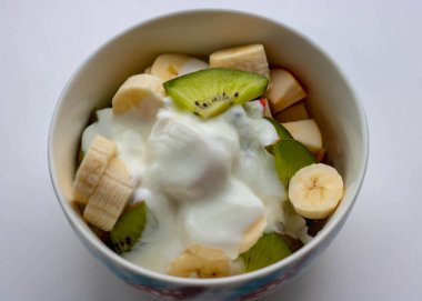 Beyaz arka planda yaban mersini ve kaşık dolu bir kasede yoğurt