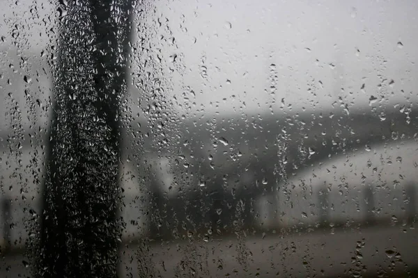 Conducir un coche bajo el puente bajo fuertes lluvias. Carretera, tráfico, luces, cruzar puentes ver a través de la ventana del coche. Lluvia cae en la ventana del coche. Fondo borroso — Foto de Stock