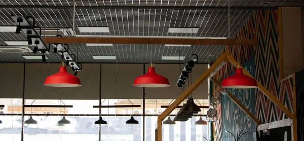 Three red decorative lamps hang from the ceiling of the cafe