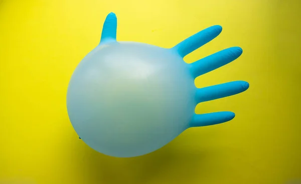 在黄色背景上以气球的形式飞行的蓝色橡胶外科手套 带有一个空间的复制品 简约主义的概念 — 图库照片