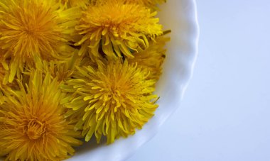 Beyaz bir tabakta karahindiba çiçekleri reçel hazırlar. Karahindibalar reçel için toplanır.