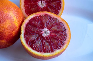 Gri arkaplanda izole edilmiş beyaz seramik bir tabakta taze turuncu mandalina grubu..