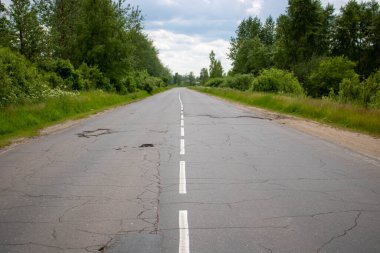 Yeşil bir ormanın ortasında düz, eski bir otoyol.