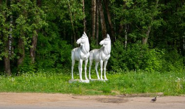 Yeşil bir ormanın arka planında beyaz geyik heykeli