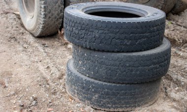 Üç eski lastik istiflenmiş, bir kamyon lastiğine yakın çekim. Çevre kirliliği. Lastikleri boşalt.