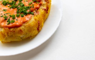 Beyaz tabakta soslu ve otlu patates güveci.