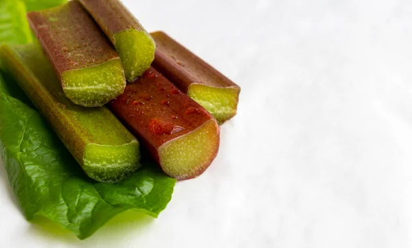 Un montón de tallos de ruibarbo rojo-verde con gotas de agua sobre un fondo blanco. El concepto de comida saludable. espacio para texto —  Fotos de Stock