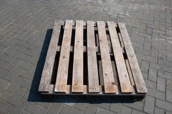 Na chodníku leží stará dřevěná paleta — Stock fotografie