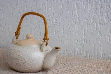 Beyaz arka planda çatlaklar ve çizikler olan eski bir hafif kil çaydanlık.