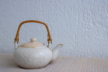 Beyaz arka planda çatlaklar ve çizikler olan eski bir hafif kil çaydanlık.