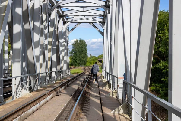 A man is walking on a railway bridge.