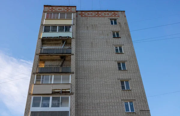 Dokuz katlı tuğladan bir apartman. Evin ön cephesindeki metal merdiven balkonlardan geçiyor..