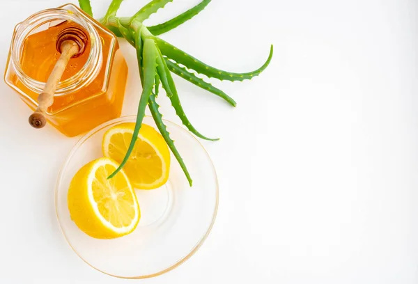 Beyaz arka planda bağışıklık sistemini güçlendirmek için kullanışlı malzemeler. Kavanozda bal, limon ve aloe vera. Metin için boşluk.