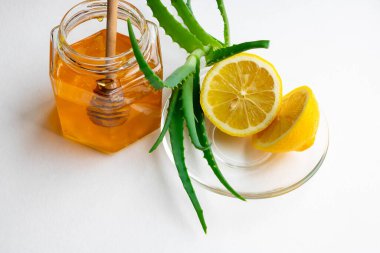 Beyaz arka planda bağışıklık sistemini güçlendirmek için kullanışlı malzemeler. Kavanozda bal, limon ve aloe vera. Metin için boşluk.