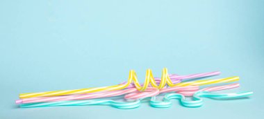 Mavi, mor, pembe, sarı renklerde pipet içmek mavi arka planda yatar..