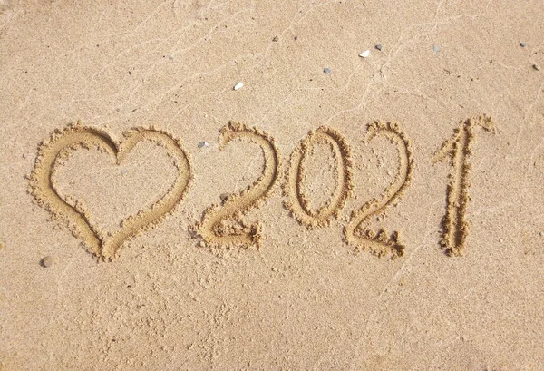 Yeni yıl konsepti. Kalp ve 2021 numara kumda. Yaz tatili. Mesaj elle yazılmış..