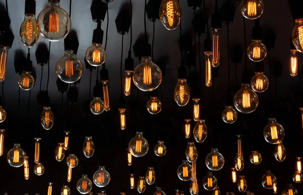 Tavanın siyah arka planında Retro Edison lambası. Kavram fikri.