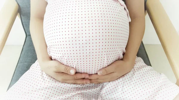 Young pregnant woman sit and holding her hand on her swollen belly .the baby inside body