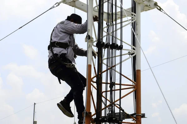 man working on high tower or pole of telecommunication.Working with high risk.Maintenance on tower.technician climbing tower for maintenance work.