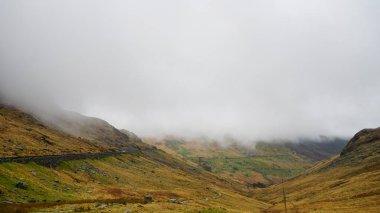 Kışın Snowdon'da yapılan bir yürüyüş sırasında yakalanan göl, engebeli vadi ve karamsar gökyüzünü n üstünden çarpıcı dağ manzarası (Snowdonia Ulusal Parkı, Galler, Birleşik Krallık)