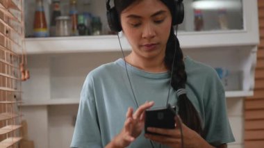 Genç Asyalı kadın mutfakta akıllı telefon kullanıyor.. 