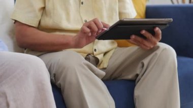 Evde kanepede oturan online alışveriş arama tablet kullanarak adam asya yaşlı çift kapatın.