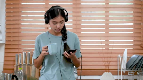 Mladá Asijská Žena Poslech Hudby Smartphone Pití Kávy Kuchyni Doma — Stock video