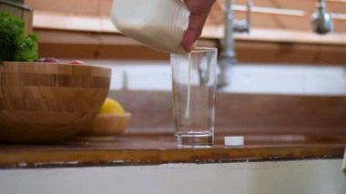 Close Up el üst düzey Asyalı adam evde mutfakta bir bardağa dökülen süt bir şişe tutan.