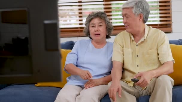 Азиатская Старшая Пара Сидит Диване Гостиной Смотрит Телевизор Дома — стоковое видео
