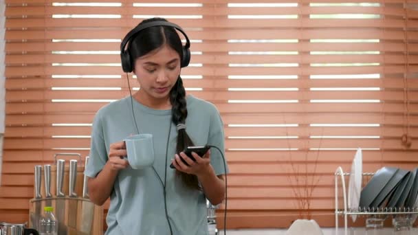 Молодая Азиатка Пользуется Мобильным Телефоном Дома Пьет Кофе — стоковое видео