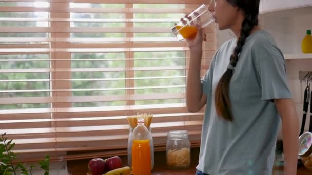 Счастливая Молодая Азиатская Женщина Пьет Апельсиновый Сок Кухне Дома — стоковое видео