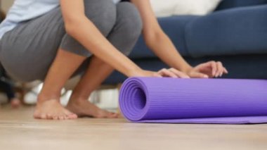 Genç asyalı kadın evde oturma odasında güvenli ve rahat yoga asanas gerçekleştirmek için yoga mat haddeleme.