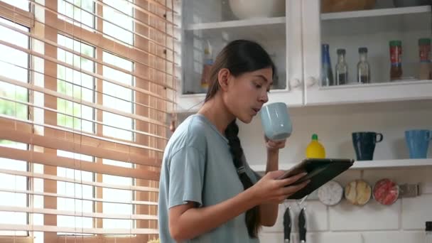 Junge Asiatin Benutzt Tablette Der Küche Hause Und Trinkt Kaffee — Stockvideo