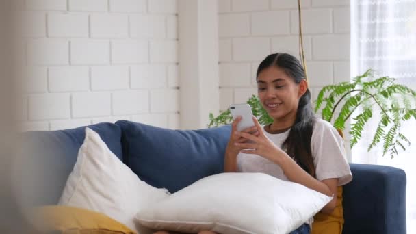 Sonriendo Mujer Asiática Sentada Sofá Uso Teléfono Inteligente Sala Estar — Vídeo de stock