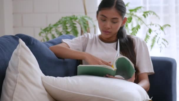 Mujer Asiática Leyendo Libro Teléfono Celular Sofá Sala Estar Casa — Vídeos de Stock