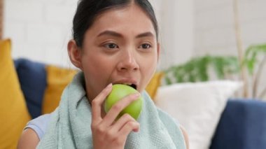Genç Asyalı kadın evde elma yerken çok mutlu..