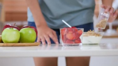 Evde mutfakta sağlıklı bir kahvaltı pişirme çilek smoothies yapmak için Asyalı kadın malzemeler kadar kapatın. yüksek açı çekim.