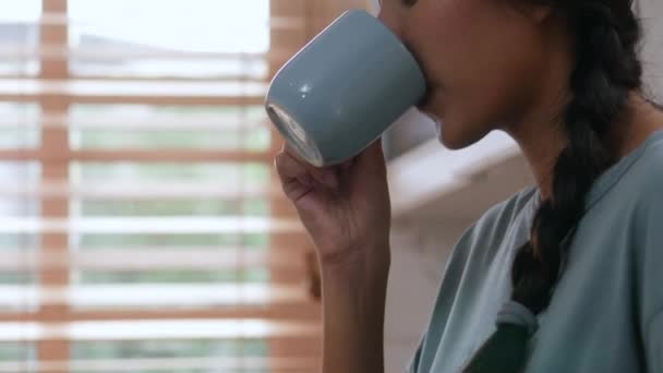 自宅で携帯電話を使ってコーヒーを飲むアジアの若い女性の笑顔をクローズアップ — ストック動画