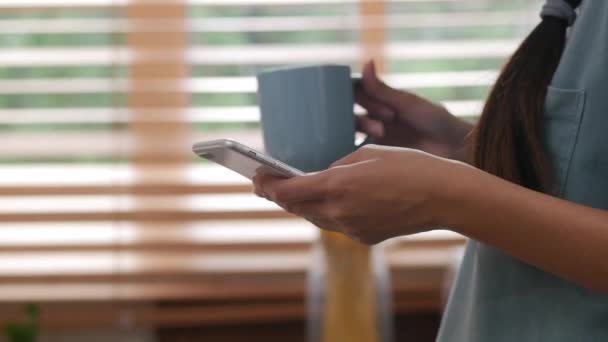 Close Genç Asyalı Kadın Evde Cep Telefonu Kullanarak Kahve Içme — Stok video