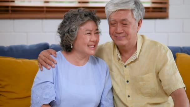 亚洲老年夫妇爱看着相机微笑坐在家里的陌生人的身上 — 图库视频影像
