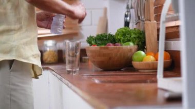 Yakın el kıdemli adam cama su döküyor ve evde mutfakta içme.