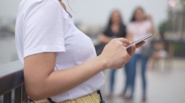 Genç Asyalı kadınlar halka açık parklarda akıllı telefon kullanıyor. Yavaş çekim yakın. arama internet, online teknoloji.