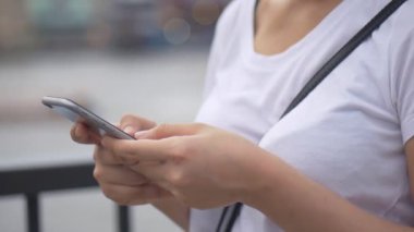 Genç Asyalı kadınlar halka açık parklarda akıllı telefon kullanıyor. Yavaş çekim yakın. arama internet, online teknoloji.