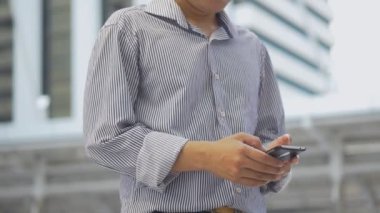 Portre Asyalı işadamı kentsel şehir arka planda bir akıllı telefon bir arkadaşı ile metin ayakta, sosyal medya arıyor.
