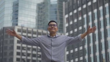 Portre yakışıklı Asyalı işadamı bir çalışma dan sonra başarı ve başarı bir kentsel şehir etrafında bakarak ayakta var. Yavaş çekim düşük açı çekimi.
