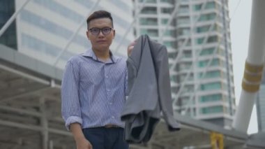 Portre yakışıklı Asyalı işadamı gülümseyerek ve şehir şehir ayakta kameraya bakıyor. Büyük bir ofis binasının yanındaki sokakta gözlüklü Asyalı bir adam. Yavaş çekim düşük açı çekimi.