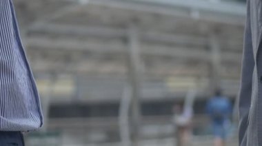 Asyalı işadamı bir çalışma dan sonra yakın el sıkışma başarı ve başarı bir kentsel şehirde ayakta var. Yavaş çekim düşük açı çekimi.